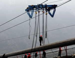 Hand pulled haws are used for the construction of the catwalk on the Huajiang Canyon Bridge